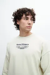 Buzo celeste de corte holgado con cuello redondo y puños y cintura acanalados. Estampado frontal con texto "Sunset Whispers" en color azul.