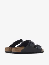 Sandalia de dos tiras ajustables con hebillas metálicas, color negro mate. Presenta la clásica plantilla anatómica de corcho y látex con forro de ante y suela de EVA.