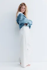 Pantalón de jogging de corte ancho y tiro alto, color gris melange, confeccionado en tejido de felpa con interior cepillado suave. Posee cintura elástica fruncida con cordón de ajuste oculto, bolsillos laterales y un bolsillo trasero abierto.