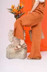 Sandalia negra de plataforma gruesa con dos tiras anchas ajustables con hebilla. Una de las tiras tiene un estampado de vaca blanco y negro.