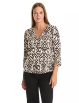 Blusa de seda fría con estampado geométrico tipo ikat en tonos beige y negro. Presenta escote en V, botones decorativos en la parte frontal y mangas tres cuartos con detalle de tajo en los puños.