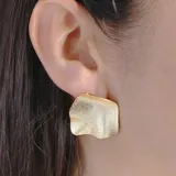 Aros de metal dorado con forma irregular y textura martillada.