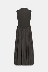 Vestido largo sin mangas con cuello subido, confeccionado con una parte superior lisa y falda de tul con caída fluida. Cuenta con cierre de cremallera oculta en la espalda.