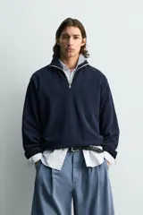 Sudadera regular fit azul marino confeccionada en tejido de algodón con estructura piqué. Cuenta con cuello subido, cierre frontal de cremallera corta y mangas largas con acabados en rib.