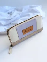 Billetera de cuero color lila, beige y blanco, con cierre metálico y monedero interno.