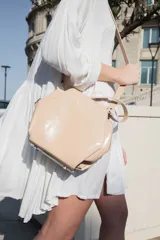 Bolso bandolera de cuero sintético blanco, lila y verde, con forma hexagonal y correa larga verde ajustable.