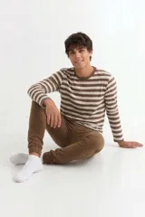 Conjunto de pijama compuesto por una remera de manga larga a rayas horizontales en tonos marrón y beige, y un pantalón tipo jogging color marrón con puños elásticos en los tobillos.