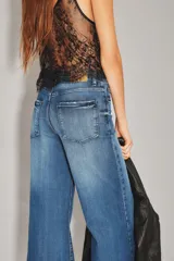 Jean de corte palazzo con tiro alto y pierna ancha, confeccionado en denim de lavado azul oscuro con efecto desgastado.