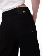 Pantalón de jean estilo wide leg color negro, con diseño de cinco bolsillos, cierre de cremallera y botón metálico.