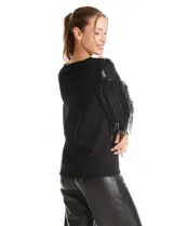 Buzo de tejido negro con mangas largas de microtul transparente, decoradas con bordados de lentejuelas y flecos brillantes. Presenta un diseño elegante con cuello redondo.