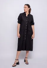 Vestido largo negro de lino y viscosa, abotonado al frente con alforzas en la parte central, mangas largas con elástico en los puños y cuello camisero.