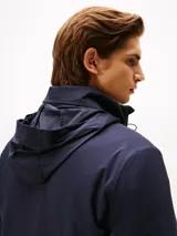 Campera ligera azul marino con cuello alto y cierre frontal de cremallera. Presenta un pequeño logo bordado de Tommy Hilfiger en el pecho.