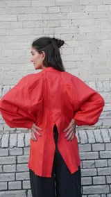 Camisa de lino blanca, de corte oversize, con mangas largas abullonadas, cuello mao y botones. Es más larga en la parte trasera e incluye un tajo en la espalda.