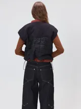 Chaleco de corte cuadrado con diseño bicolor en tonos terracota y crema. Presenta cierre frontal metalizado, parches de nylon en el pecho, interior forrado en corderito y cordón ajustable en el ruedo.