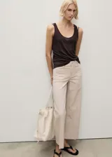Pantalón estilo jeans de corte wideleg, color beige, con tiro medio, cierre de botón y cremallera, trabillas para cinturón y dos bolsillos de parche frontales.