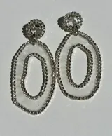 Aros colgantes plateados con diseño de doble óvalo concéntrico y detalle circular en el lóbulo, completamente recubiertos de cristales brillantes.