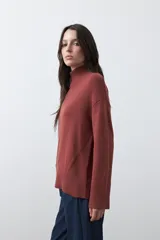 Polera de tejido liviano en color negro, con cuello alto, mangas largas y corte relajado. Presenta un diseño minimalista con recortes laterales que aportan estructura a la prenda.