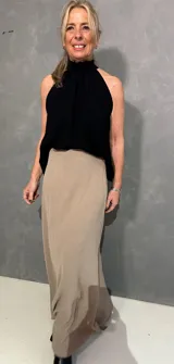 Musculosa negra sin mangas con cuello halter fruncido, confeccionada en tejido liviano de caída fluida.