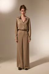 Pantalon de vestir de corte ancho y tiro alto, confeccionado en tela de viscosa con acabado satinado. Presenta cintura elástica y diseño fluido.