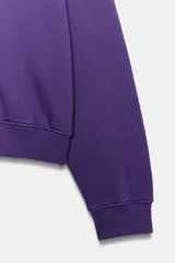 Sudadera lavada Fruit of the Loom, color morado, de cuello redondo con detalle de costura triangular, manga larga y calce holgado. Presenta un pequeño bordado con el logo de la marca en el pecho y acabados en rib elástico en cuello, puños y ruedo.