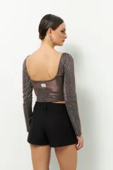 Top plateado brillante de manga larga y cuello redondo.