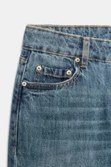 Jeans de tiro medio con corte slim leg, confeccionados en denim color beige. Presentan cintura con trabillas, diseño clásico de cinco bolsillos y cierre frontal con cremallera y botón metálico.