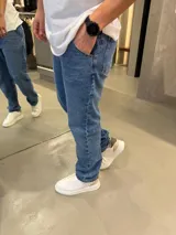 Jean de corte mom con calce regular, confeccionado en denim de tono azul medio. Presenta diseño clásico de cinco bolsillos y cierre frontal.