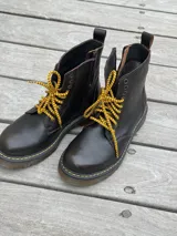 Bota corta de cuero color chocolate, con cordones amarillos y cierre lateral.