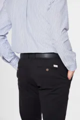 Pantalón de gabardina color marrón claro, corte slim fit, con bolsillos laterales y traseros. Se ajusta a la cintura con cinturón de cuero marrón.