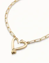 Collar dorado con cadena de eslabones alargados y dije central con forma de corazón estilizado, con la inscripción "UND & 50" en la parte inferior.