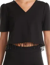 Blusa negra de corte corto con escote en V, mangas cortas con sutil efecto abullonado en los hombros y ruedo decorado con flecos de cuentas negras.