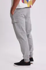 Pantalón deportivo tipo jogger en color gris claro, con diseño cargo que incluye bolsillos laterales. Presenta cintura elástica con cordón ajustable y puños elásticos en los tobillos.
