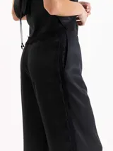 Pantalón palazzo de tiro alto color negro, confeccionado en twill de viscosa con caída fluida. Cuenta con cintura clásica con presillas, pinzas frontales, bolsillos laterales y una delicada aplicación de puntilla de encaje a lo largo de ambos laterales.