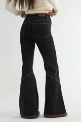 Jean de corte flare en color negro, con costuras verticales decorativas en contraste y ruedo deshilachado.