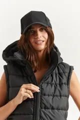 Chaleco negro oversize con capucha forrada en tela gamuzada, cierre metálico YKK, bolsillos laterales y tancas regulables en el ruedo.