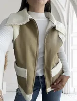 Chaleco color beige con interior de corderito blanco, cierre frontal con cremallera y bolsillos laterales.