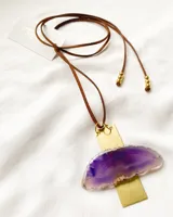 Collar con dije de piedra ágata morada y engarce de latón dorado, con tira de cuero marrón ajustable.