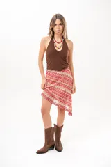 Pollera midi de corte asimétrico con tejido de crochet y patrón en zigzag multicolor en tonos rojo, rosado y beige.
