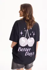 Remera negra de manga corta y corte holgado, con estampa en la espalda de cerezas en forma de bolas de espejo y la leyenda 'Better Days' en tonos rosados.