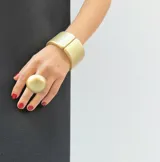 Anillo de diseño minimalista con forma de media esfera de resina en acabado mate, montado sobre una base de acero dorada regulable.