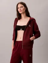 Jogger de felpa color bordó, de corte tapered y tiro medio, con cintura elástica y bolsillos laterales. Cuenta con puños ajustados en los tobillos y detalle del monograma de Calvin Klein en la pierna.