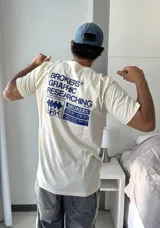 Remera beige de manga corta con estampado gráfico en azul en la espalda que incluye el texto "BROKERS GRAPHIC RESEARCHING" y "THE NEW WAVE BROKERS".