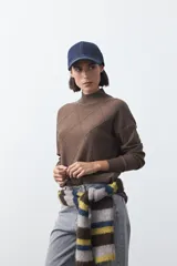 Polera de tejido de punto color gris oscuro, con cuello alto y diseño de rombos en relieve en el frente. Presenta un calce relajado con terminaciones en rib en cuello, puños y ruedo.