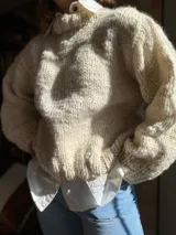 Sweater de lana color crema, tejido a mano con punto grueso.