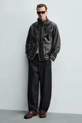 Mocasín de vestir color marrón oscuro, fabricado en piel lisa, con detalle de antifaz en el empeine y costura visible en la puntera. Presenta una horma cuadrada y suela con ligero tacón.