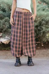 Babucha de gabardina con diseño a cuadros, corte holgado tipo bombacho y cintura elástica. Presenta bolsillos laterales y terminación ajustada en los tobillos.