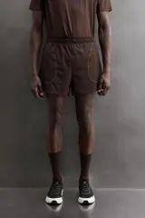 Short de running color marrón, confeccionado en tejido técnico elástico con forro interior. Cuenta con cintura elástica ajustable, bolsillos laterales con cierre de cremallera oculto y aberturas en las perneras.