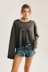 Remera de manga larga gris oscuro con efecto lavado gastado, corte oversize y cuello redondo amplio. Cuenta con estampado tipográfico manuscrito en el pecho.