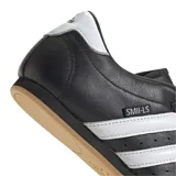 Championes Adidas modelo Taekwondo, color negro con las tres bandas características en blanco. Presentan un diseño sin cordones con empeine acolchado y suela de goma color caramelo.