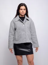 Tapado gris de corte recto con cuello solapa y cierre frontal con tres botones a tono. Tiene bolsillos laterales tipo parche.